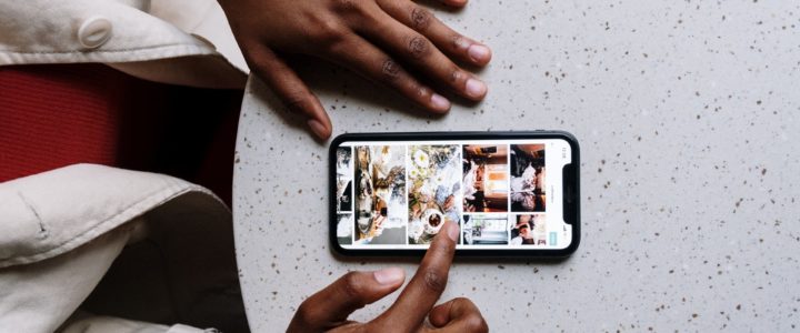Black woman's hands beside her smartphone scrolling through Instagram images