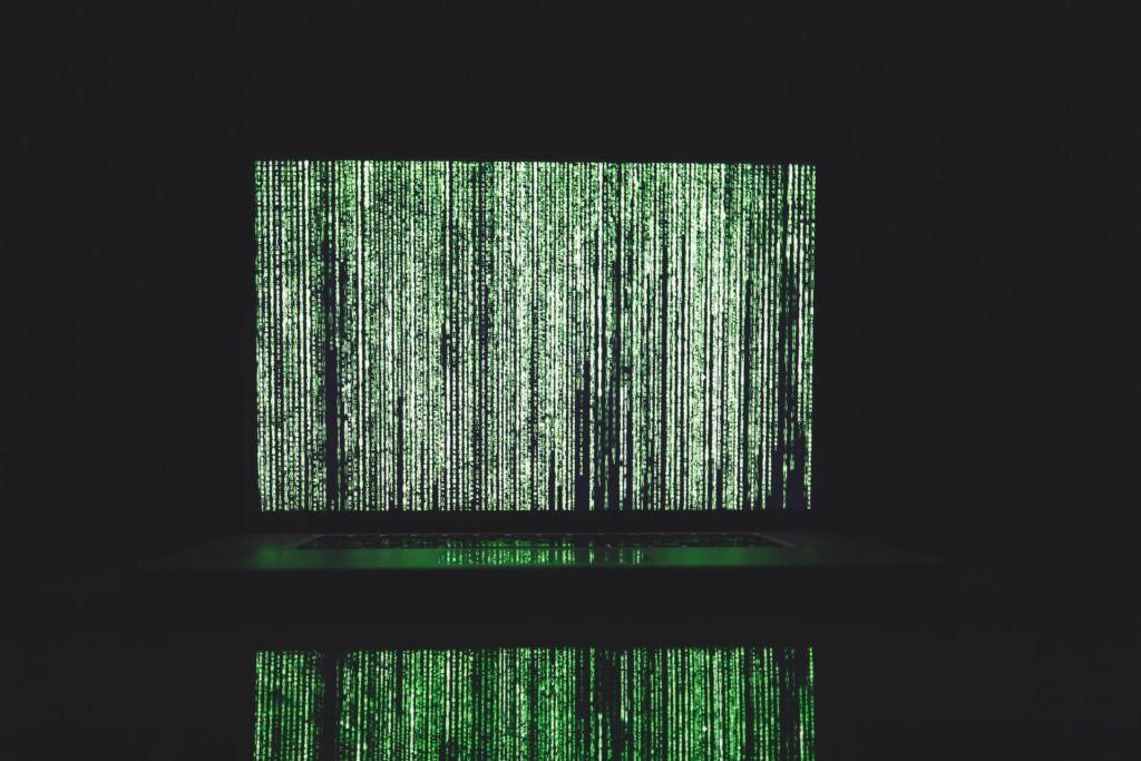 Reams of green data on black screen with reflection underneath