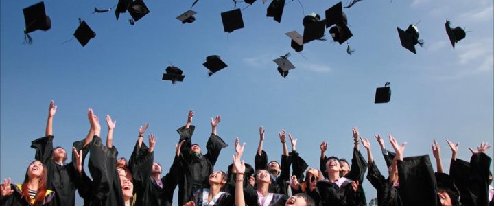 College graduation, mortar boards being thrown into the air, blue sky