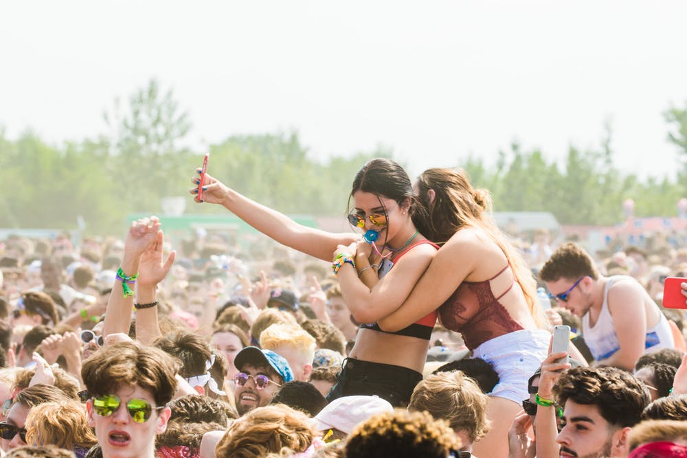 Festival crowd during the day, two women on shoulders