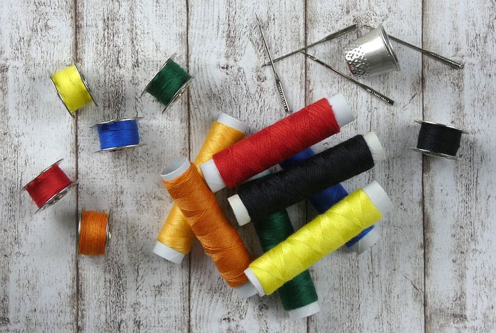 Various coloured threads and needles and a thimble