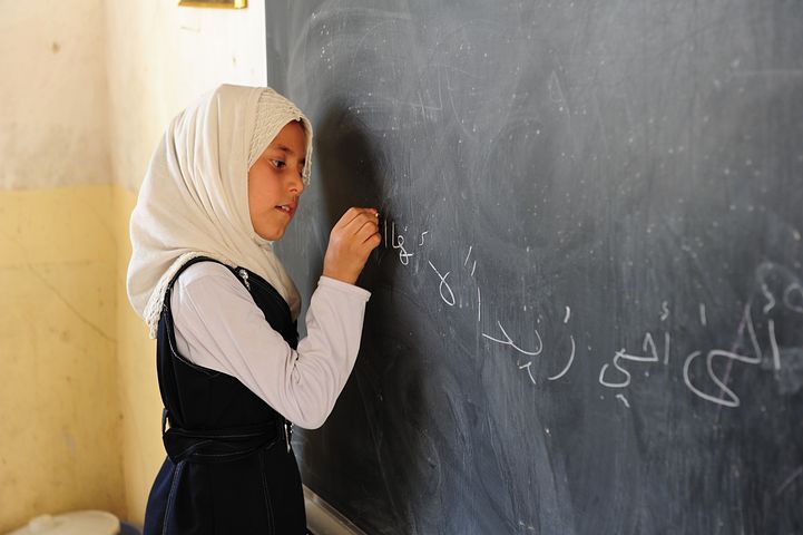 Girl with hard scarf writing on chalkboard