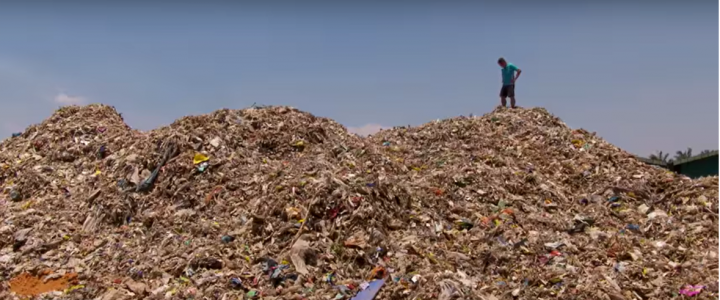 Man standing on enormous trash heap
