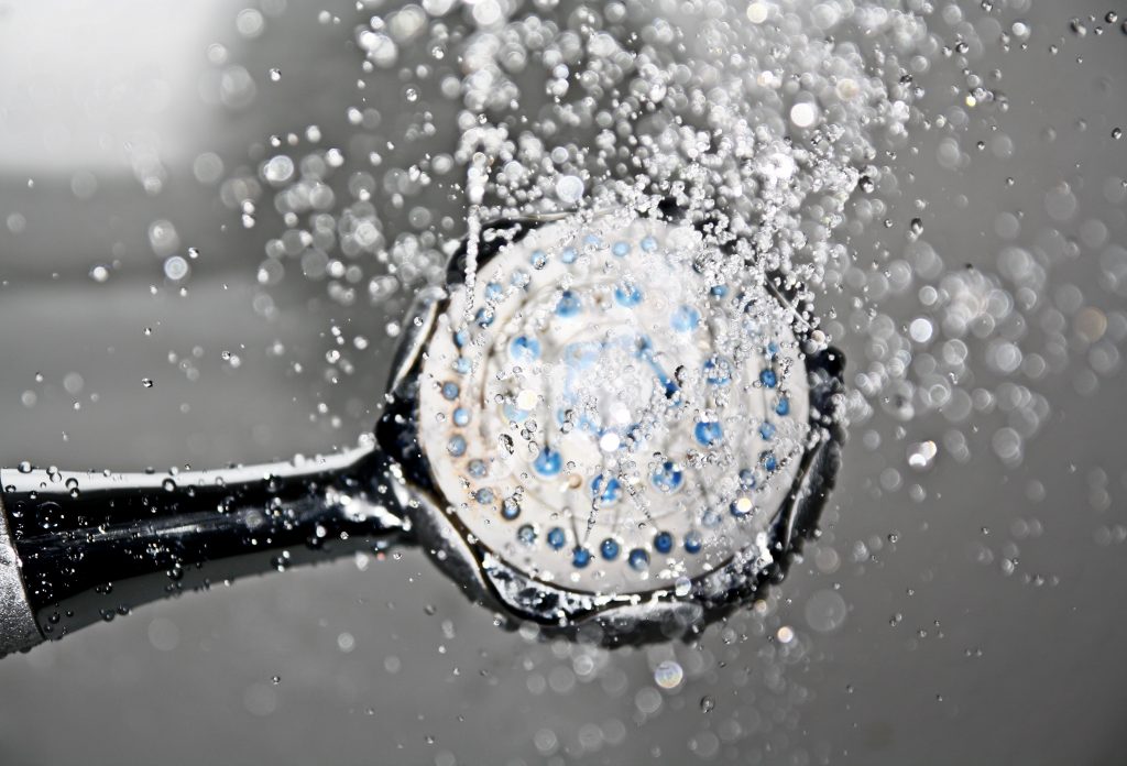 Close up of water saving shower head as water pours from above. 