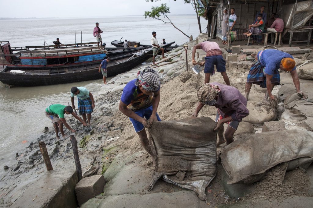 Bangladeshi people using sand bags to protect property from rising waters.