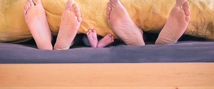 parents and baby feet form the end of a bed