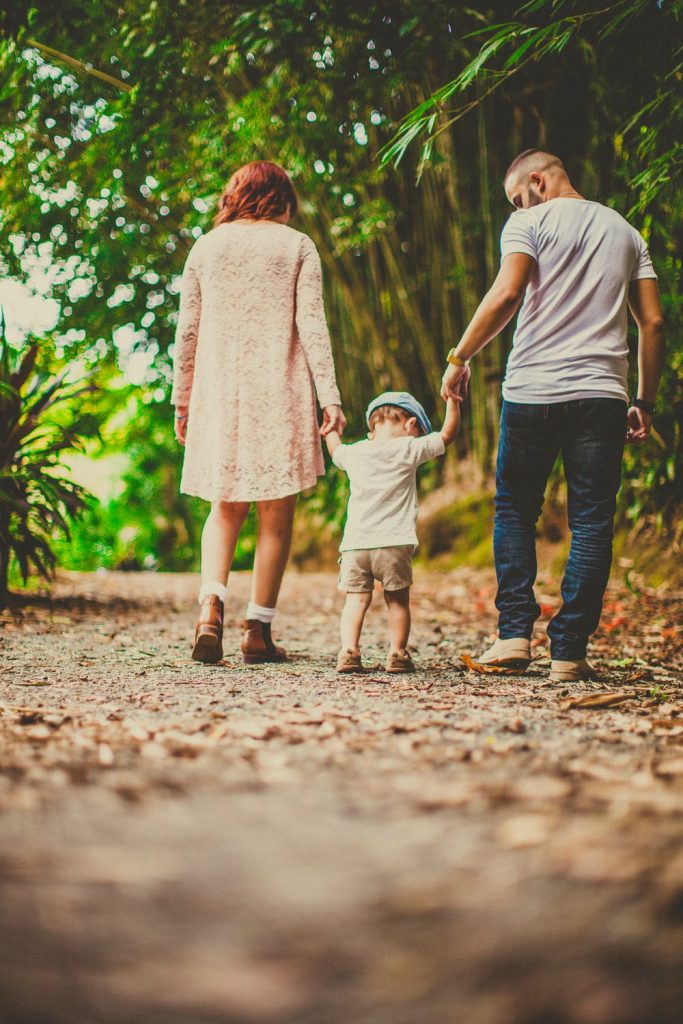Man and woman walking with a small child between them holding hands