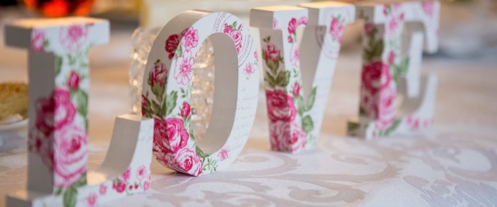 White and pink flower painted blocks that spell out "love" set on a wedding table.