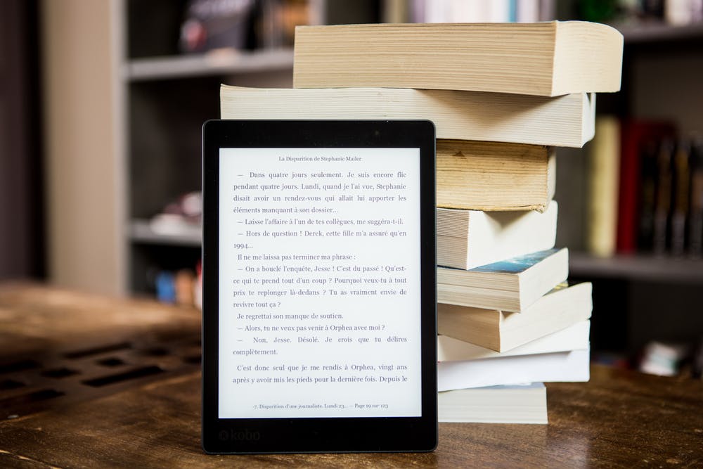 Stack of books with e-reader leaning on them