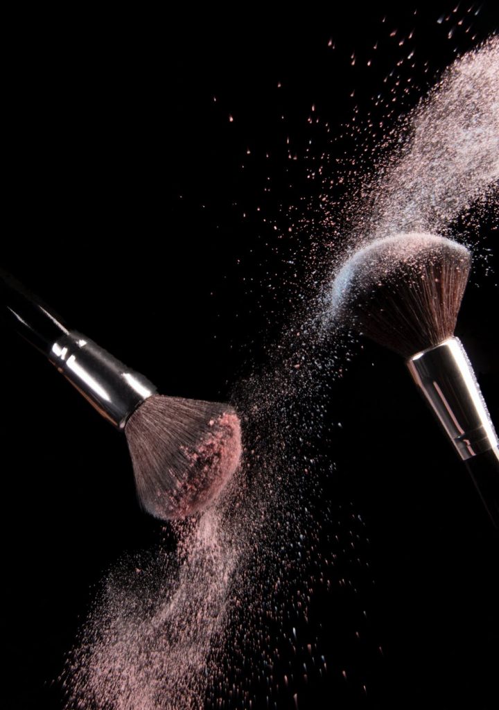 Makeup brushes with powder flying off them