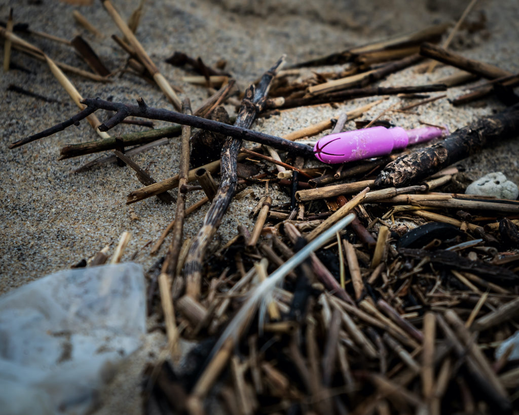 Pink tampon applicator littered on beach. Sustainable period items.