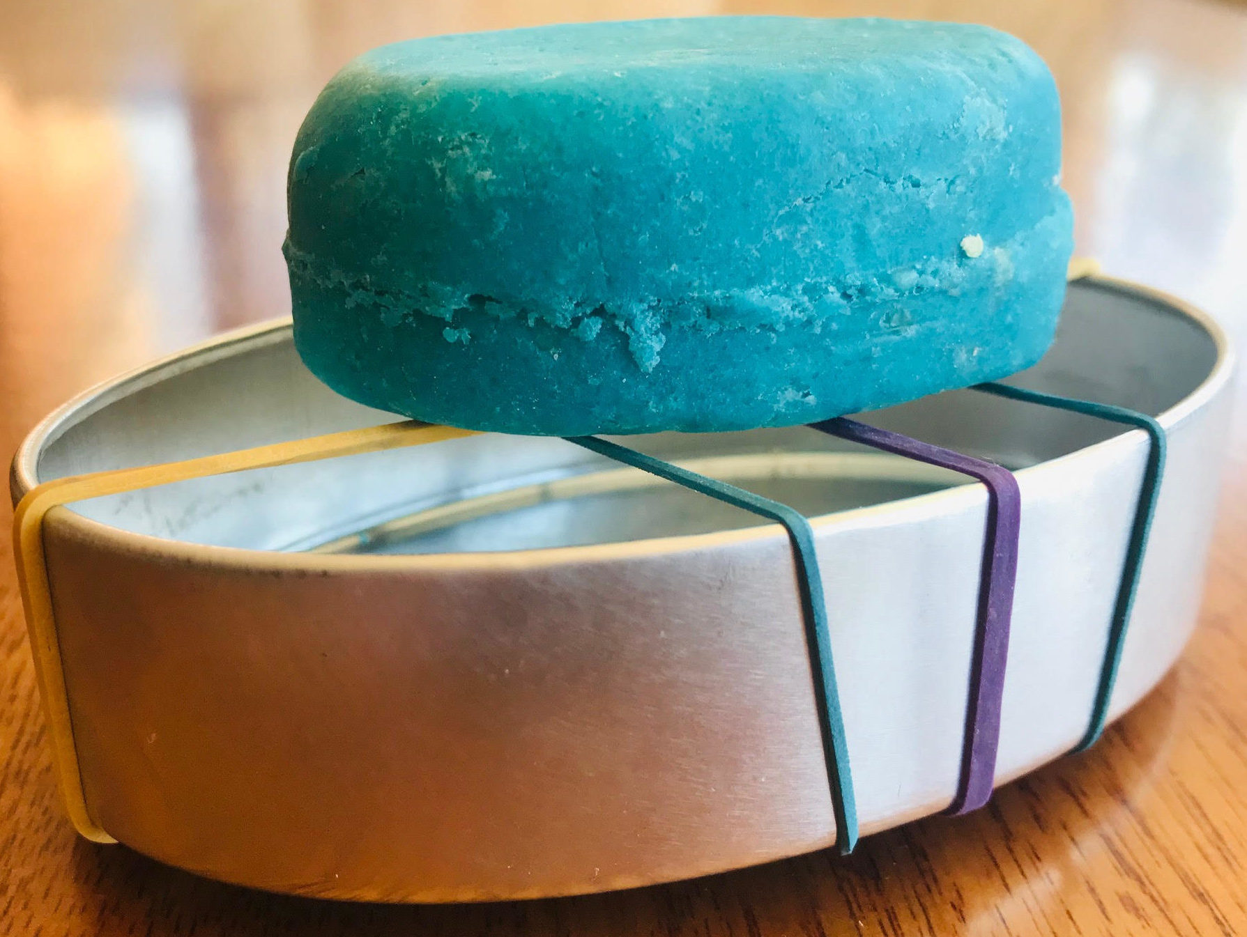 Solid conditioner bar on homemade draining rack with elastic bands wrapped around a tin