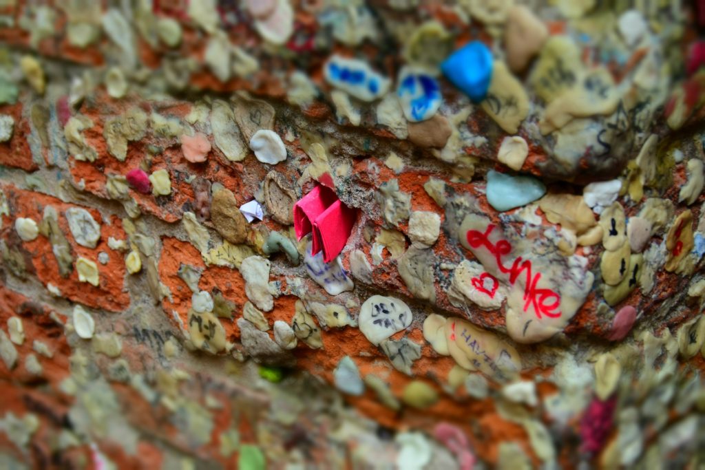 hundreds of blobs of chewed up chewing gum stuck to a wall 