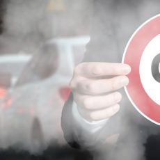 Car exhausts and man holding speed limit sign saying CO2