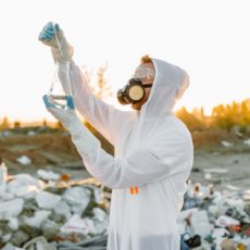 Man in protective clothing and gas mask measuring toxicity of a substance