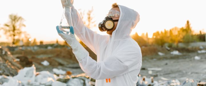 Man in protective clothing and gas mask measuring toxicity of a substance