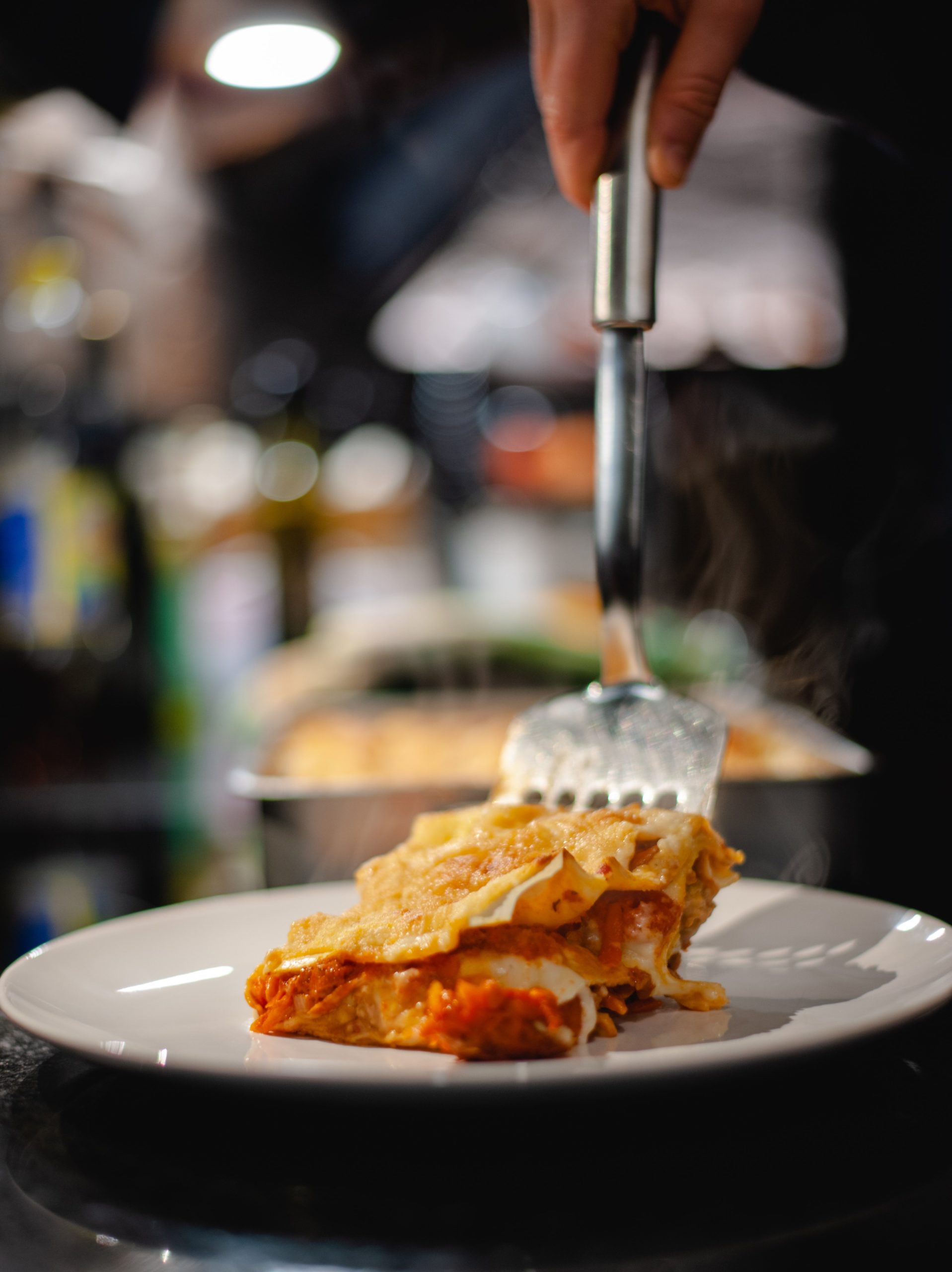 Piping hot pumpkin lasagna being served onto a plate with a silver spatula