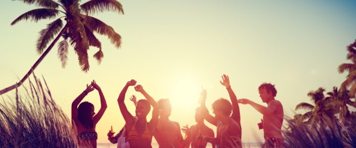 People at a beach party, dancing against a backdrop of sunset