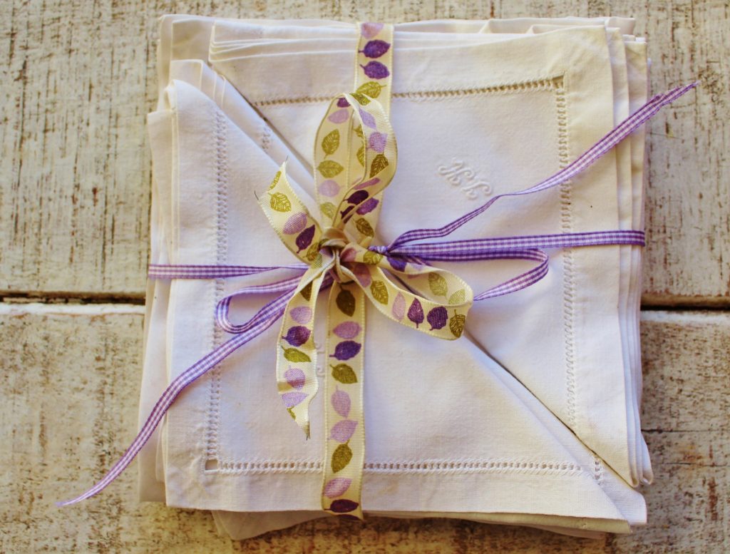 Stack of handkerchiefs being used as cloth napkins, wrapped in purple ribbon