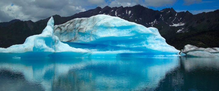 Landscape image of very blue glacier over still water