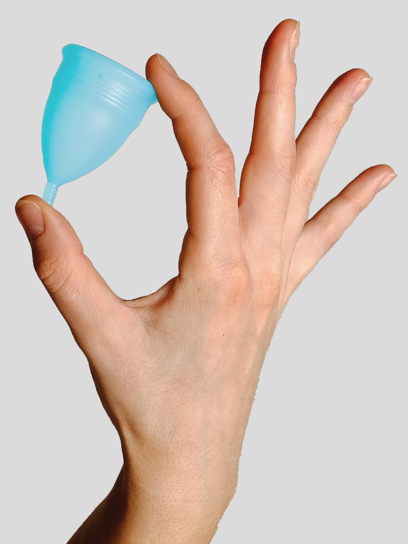 person holding a light blue menstrual cup between their index finger and thumb