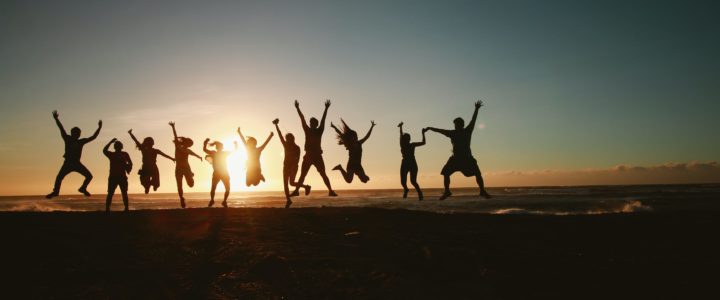 Silhouette of a group of people jumping in the air against a background of sunset