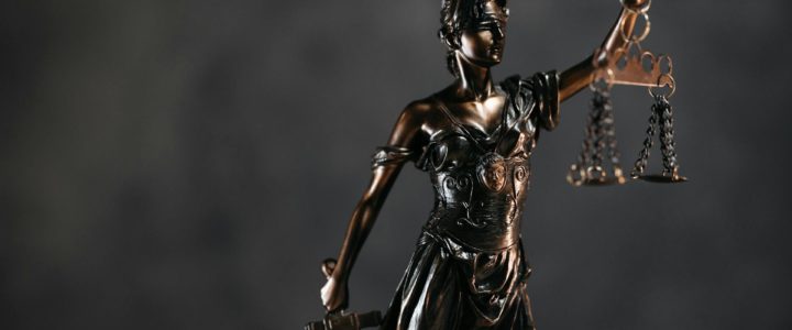 Deep bronze justice statue with scales in one hand and sword in the other