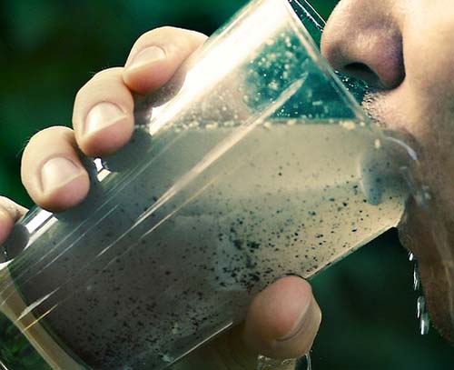 Person drinking dirty, contaminated water from a clear glass