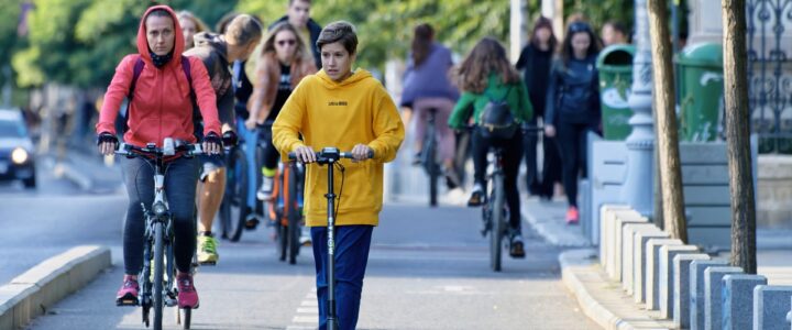 people riding scooters and bicycles in a cycle lane