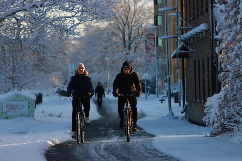 2 people riding bicycles on a snowy footpath