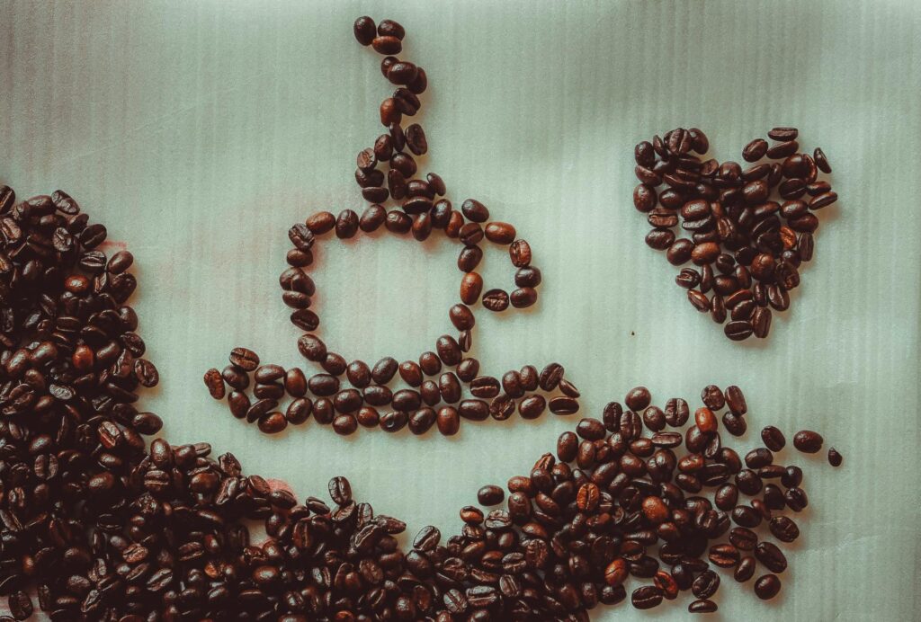 Roasted Coffee beans used to form the shape of a cup of coffee, a person with arm extended, and a love heart.