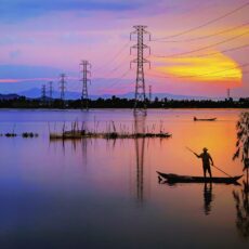 Gorgeous blue and red sunset over a lake with large power lines protrusing high above the water.