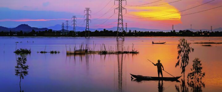 Gorgeous blue and red sunset over a lake with large power lines protrusing high above the water.